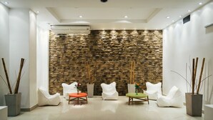 A modern interior with a stone wall, white furniture, and a tiled floor.