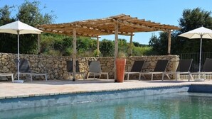 A pool area with lounge chairs and umbrellas, a stone wall, and a pergola structure. - Splendid duplex in Provence, in the middle of vineyards (Robion)