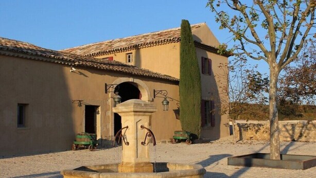 A courtyard with a fountain, a building with a tiled roof, and a tree. - Splendid duplex in Provence, in the middle of vineyards (Robion)