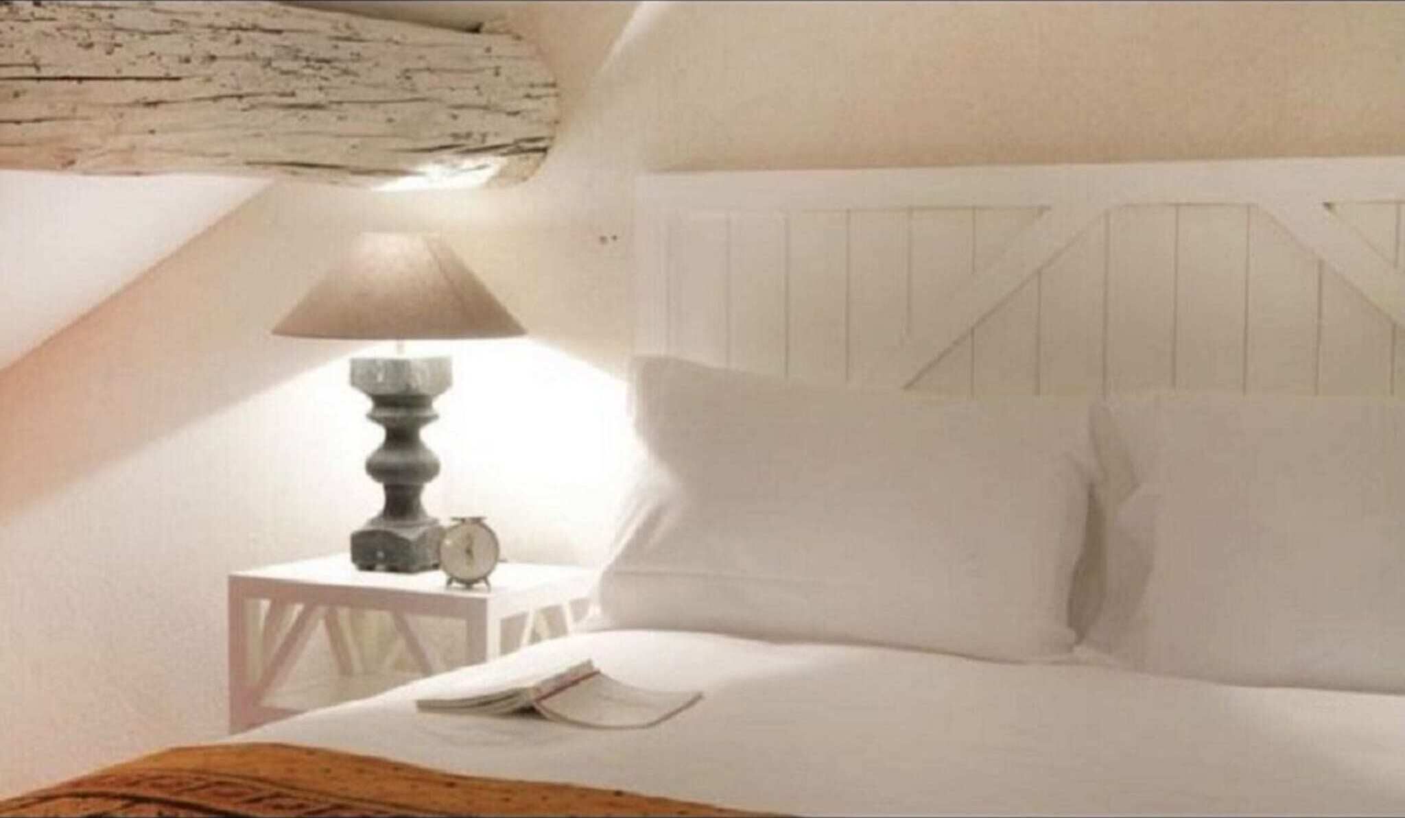 Une chambre à coucher avec un lit, une table de chevet, une lampe et une horloge.