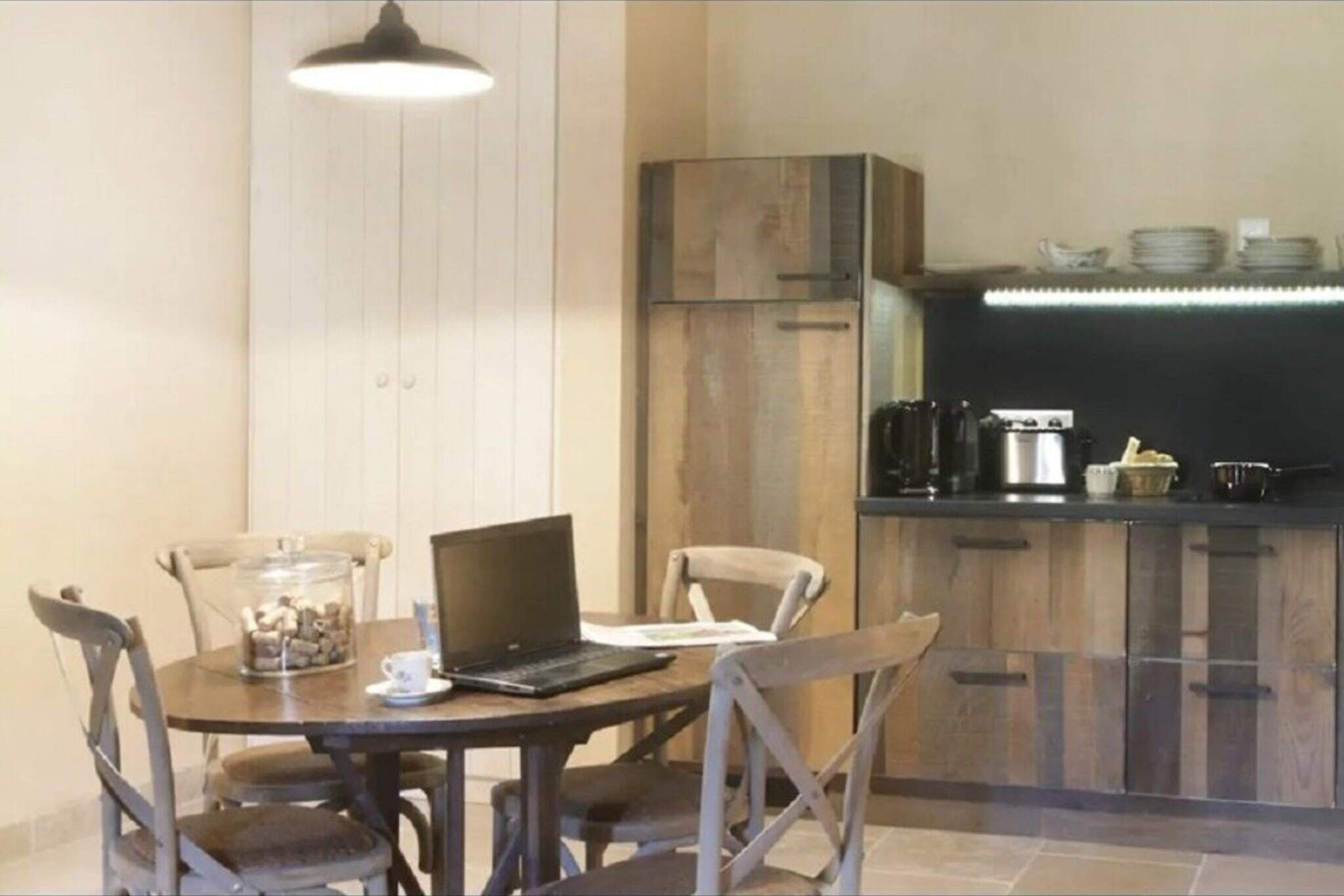 A compact kitchen with a modern design, featuring a built-in oven, a coffee maker, and a kettle on the countertop.