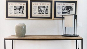 A wooden table with a metal frame, a vase, and three framed posters on the wall. - Syrah (Robion)