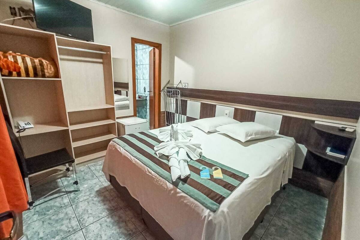 A hotel room with a bed, a wardrobe, a desk, and a mirror.