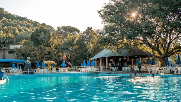 Ein Schwimmbecken mit klarem, blauem Wasser, umgeben von weißen Liegestühlen und blauen Sonnenschirmen.