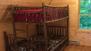 Una cama litera con colchón rojo en una habitación de madera con ventana.