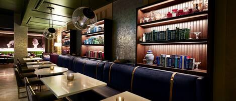 Un restaurante con cabinas, mesas y estanterías llenas de libros y cristalería.