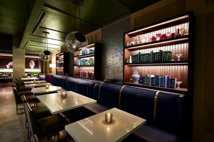 Un restaurante con cabinas, mesas y estanterías llenas de libros y cristalería.