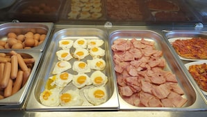 A buffet with various food options including eggs, ham, and hot dogs.