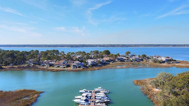 An aerial view of a coastal residential area with houses and a marina.