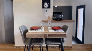 Un comedor con una mesa de madera, cuatro sillas y una cocina al fondo.