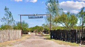 Een rustieke poort met een bord waarop staat: ‘The Hideout at Palo Duro Canyon’.