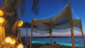 Un paisaje playero con una hamaca y una silla de playa, una estructura de madera y vistas al mar.