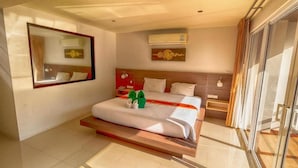 Une chambre d’hôtel moderne dotée d’un grand lit, d’un miroir, d’un appareil de climatisation et d’une porte vitrée donnant sur un balcon.