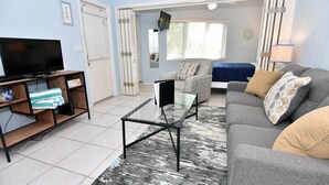 A living room with a TV, sofa, coffee table, and a patterned rug. - Morningside (Sanibel)