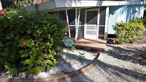 A small, single-story building with a covered porch and a door. - Morningside (Sanibel)