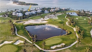 Een golfbaan met een groot meer, palmbomen en strandwoningen.