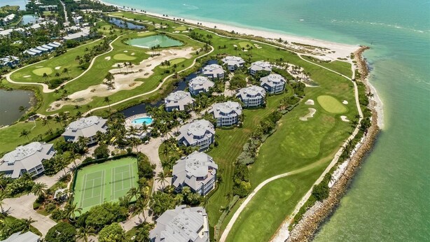 Luchtbeeld van een kustresort met meerdere gebouwen, golfbanen en een strand.