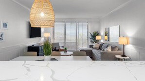 A modern living room with a white marble coffee table, a large woven pendant light, a sofa, and a TV mounted on the wall. - Beach Villas (Captiva)