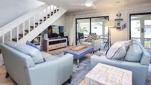 A modern living room with a staircase, a flat-screen TV, and a dining area with a table and chairs. - Beach Homes (Captiva)