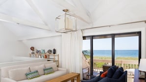 A modern living room with a sofa, a coffee table, and a view of the ocean through large windows. - Beach Homes (Captiva)