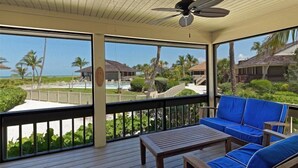 A covered outdoor area with a wooden deck, blue cushioned seating, and a ceiling fan. - Beach Homes (Captiva)