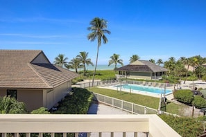 A resort with a swimming pool, palm trees, and a beach view.