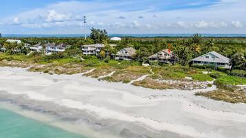 Une propriété située en bord de mer, comprenant plusieurs maisons, offrant une vue dégagée sur l’océan et un sentier menant à la plage.
