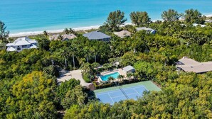 An aerial view of a residential area with a swimming pool surrounded by lush greenery and a beach in the background. - South Seas Gulf Cottage 1106 (Captiva)