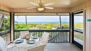 A covered outdoor dining area with a table set for two, overlooking a beach. - South Seas Gulf Cottage 1106 (Captiva)