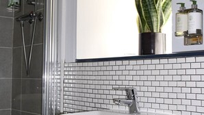 A bathroom with a glass-enclosed shower, a white sink, and a mirror above it. - The Carlton Manor Hotel (Lowestoft)
