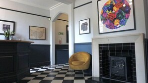 A lobby with a checkered floor, a fireplace, and framed artwork on the walls. - The Carlton Manor Hotel (Lowestoft)