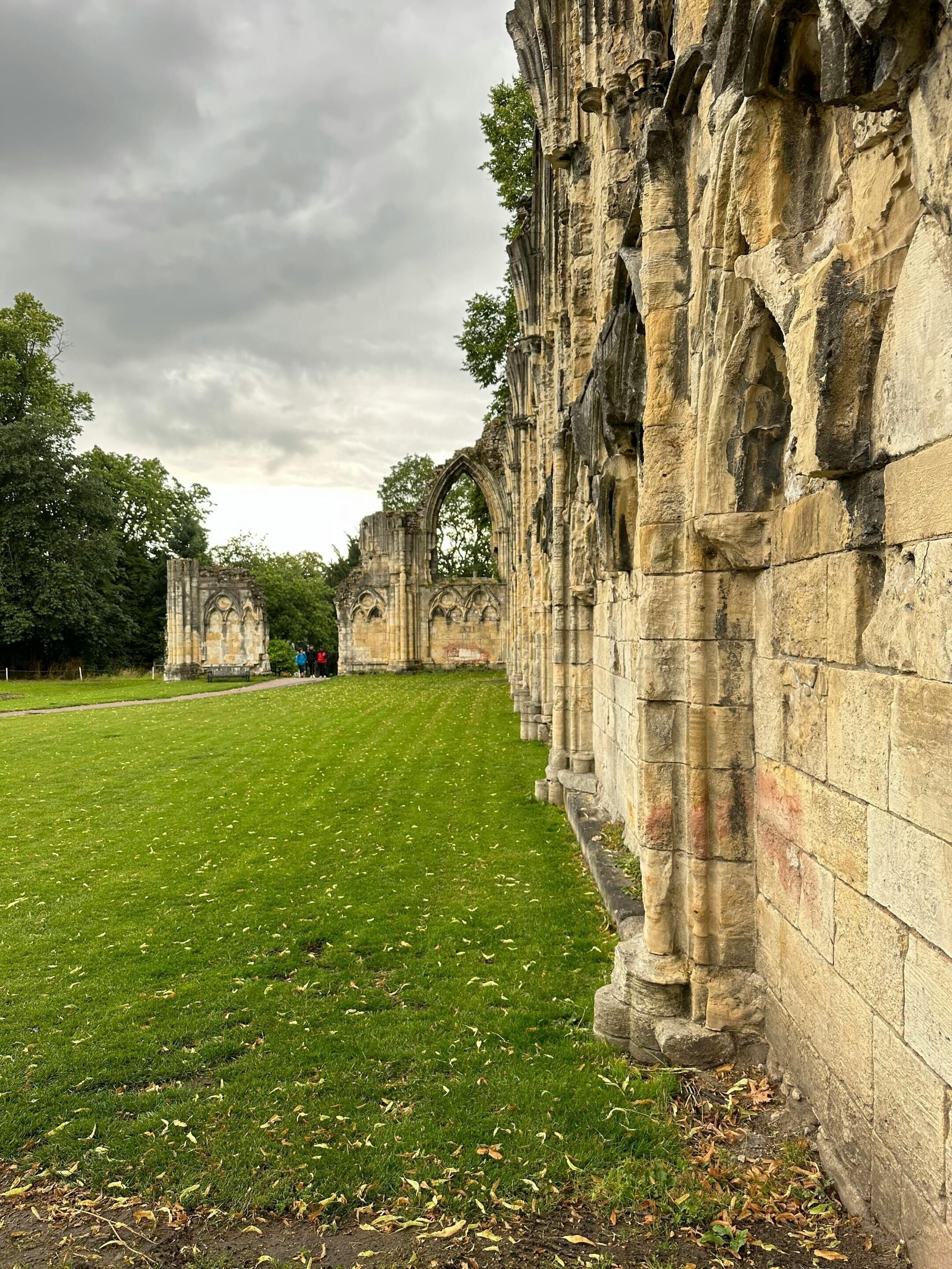 A historic stone building with arched windows and a grassy lawn.