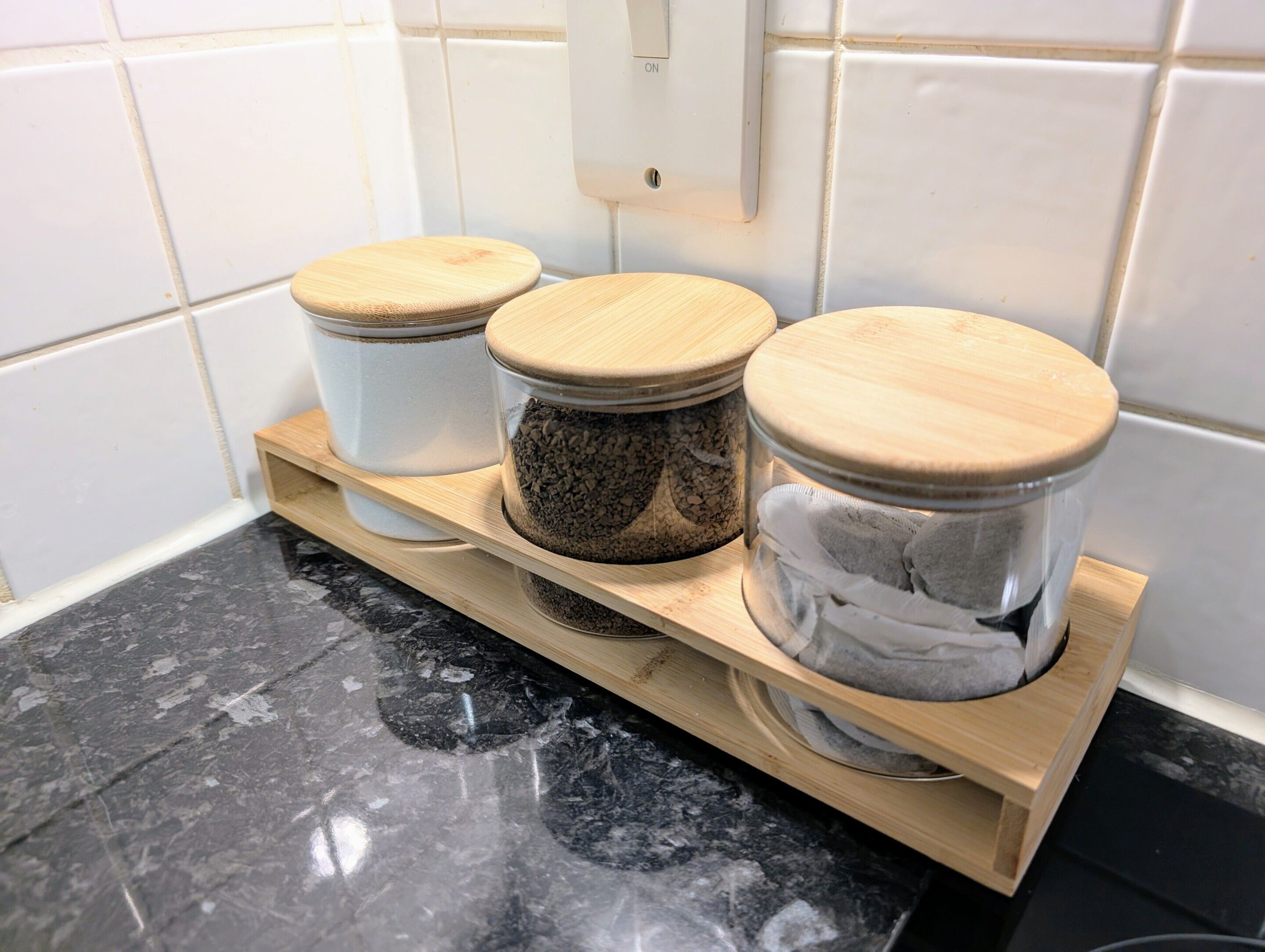 Three glass jars with wooden lids on a wooden shelf.