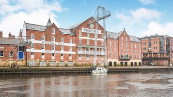 A waterfront building with multiple levels and a crane, adjacent to a river.