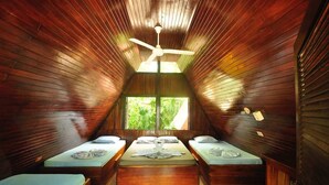Une chambre confortable située dans les combles, avec des murs en bois, un plafond en pente et un lit simple agrémenté d’un coussin décoratif en forme de cygne.