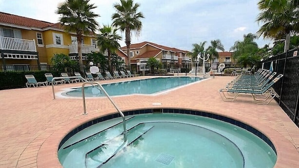 A swimming pool with a hot tub, surrounded by lounge chairs and palm trees. - Private Pool Home-popular Resort Near Disney! (Kissimmee)