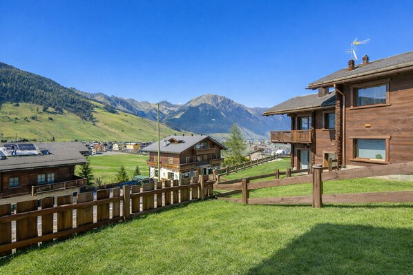 Un bâtiment en bois doté d’un balcon, d’une clôture en bois et ayant une chaîne de montagnes en arrière-plan.
