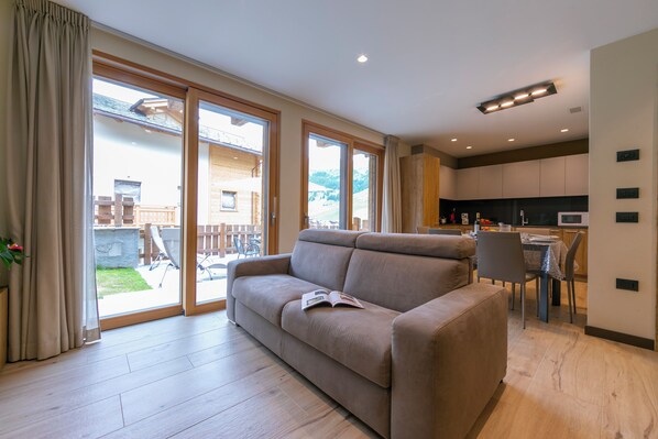 Departamento familiar, varias habitaciones (Casa Giardino Ski in - Ski out 100m) | Área de sala de estar | Televisión de pantalla plana y chimenea 