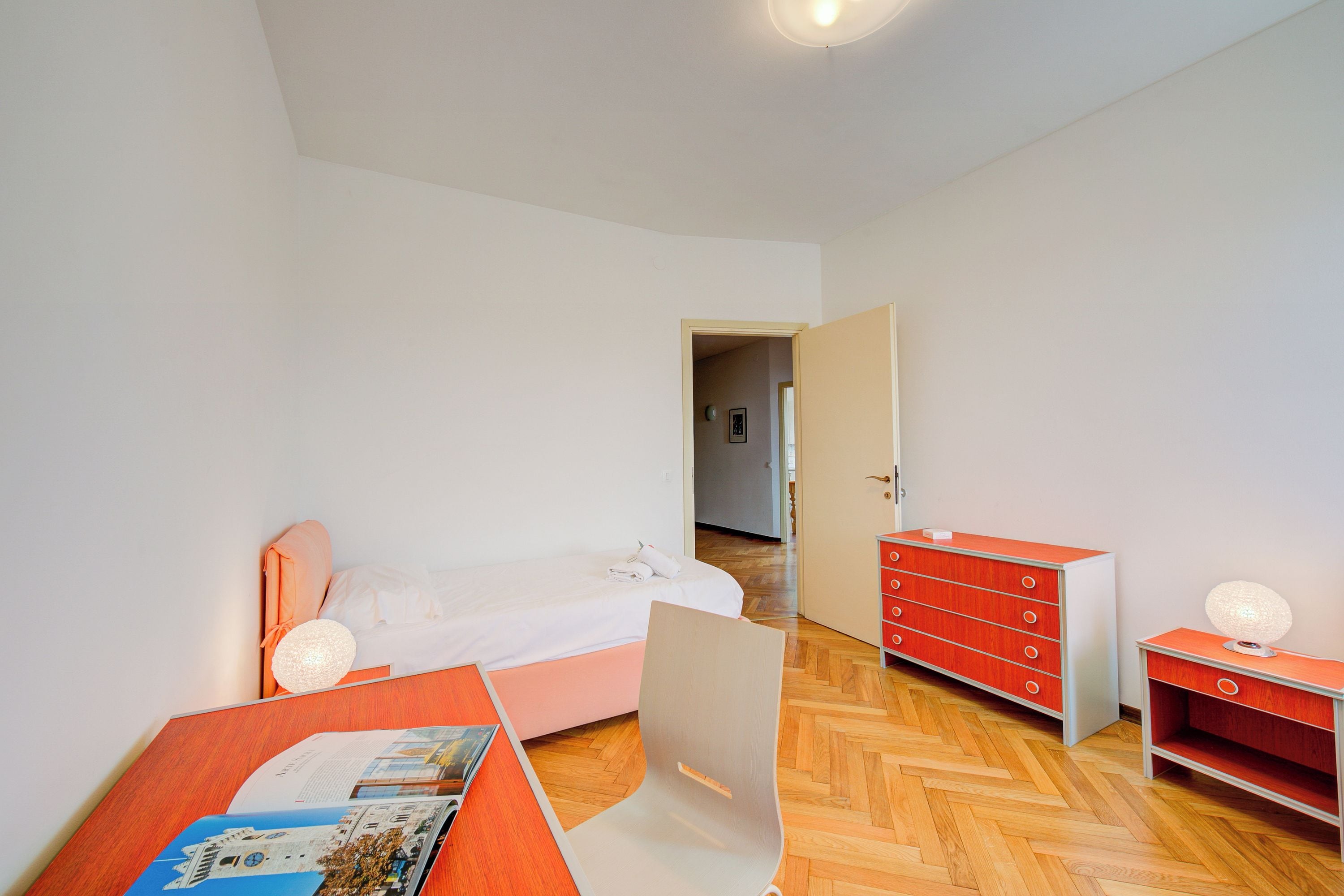 A bedroom with a bed, a desk, a dresser, and a chair.