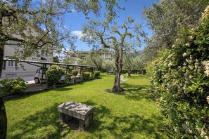 A courtyard with a stone bench, a covered seating area, and a building in the background. - Margherita Near Lake - Family Friendly (Toscolano Maderno)