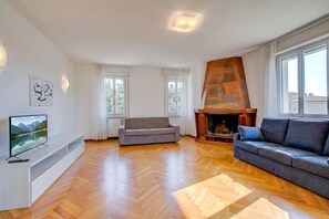 A modern living room with a fireplace, a sofa, a TV, and a herringbone wood floor. - Margherita Near Lake - Family Friendly (Toscolano Maderno)
