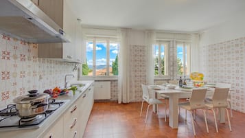 A kitchen with a stove, sink, and dining area with chairs and a table.