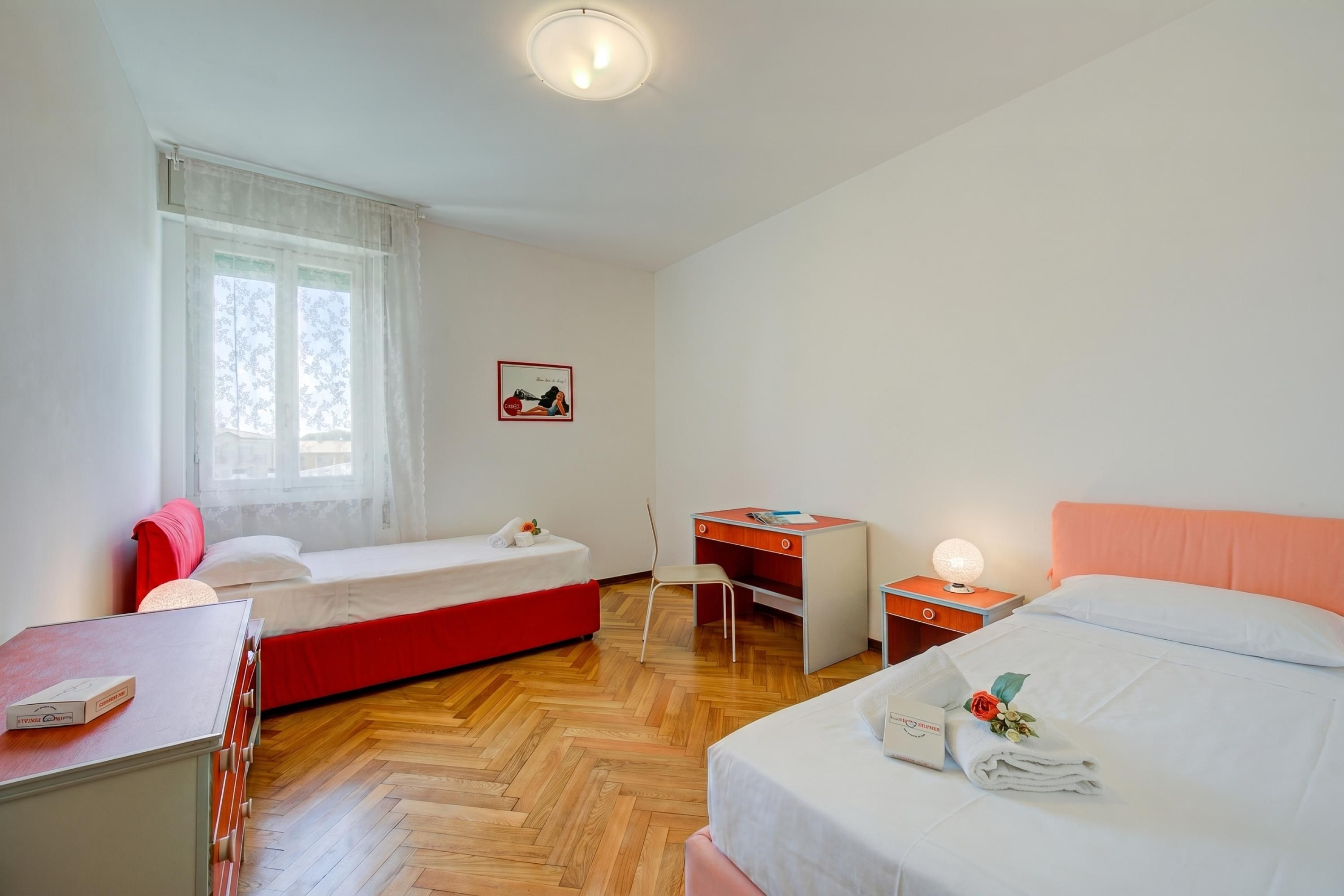 A hotel room with a bed, a desk, a chair, a small table, and a window.