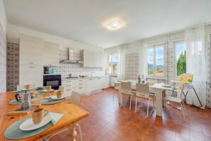 Una cucina moderna con zona pranzo, vista all'esterno e seggiolone per bambini.