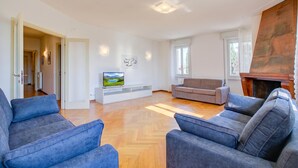 A spacious living room with a fireplace, a television, and a sofa. - Margherita Near Lake - Family Friendly (Toscolano Maderno)