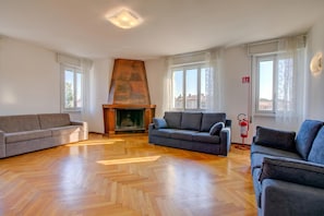 Un salon spacieux doté d’un parquet en bois à motifs en chevrons, d’une cheminée et de deux canapés.