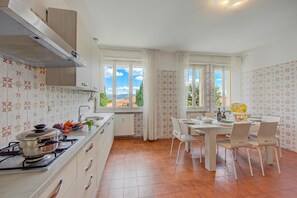 Una cucina con piano cottura, lavello e zona pranzo con sedie e tavolo.