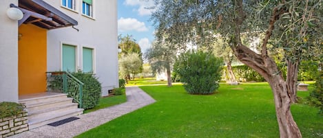 A two-story building with a yellow facade, green shutters, and a well-maintained lawn.