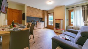 Eine moderne Küche mit Holzausstattung, einem Esstisch für zwei Personen und einem eingebauten Kamin.