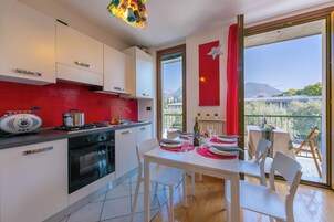 A modern kitchen with white cabinets, a red accent wall, and a dining area with a table set for two.